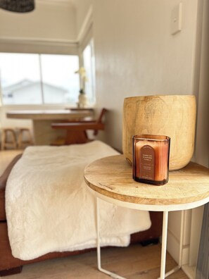 Ein Zimmer mit einem Bett, einem runden Holztisch mit Kerze und einem großen Holzpflanzgefäß.