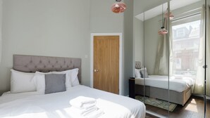 A bedroom with a bed, a mirror, and a door. - Stylish 3BDR Flat 10 Minutes from Portobello Road (Greater London)