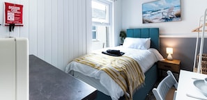 Une chambre à coucher avec un lit, une table de chevet, une lampe et un tableau au mur.