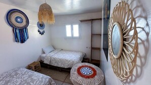 A bedroom with two beds, a small stool, a hanging light, and decorative wall art. - Jurassic Surf House Anza (Agadir)