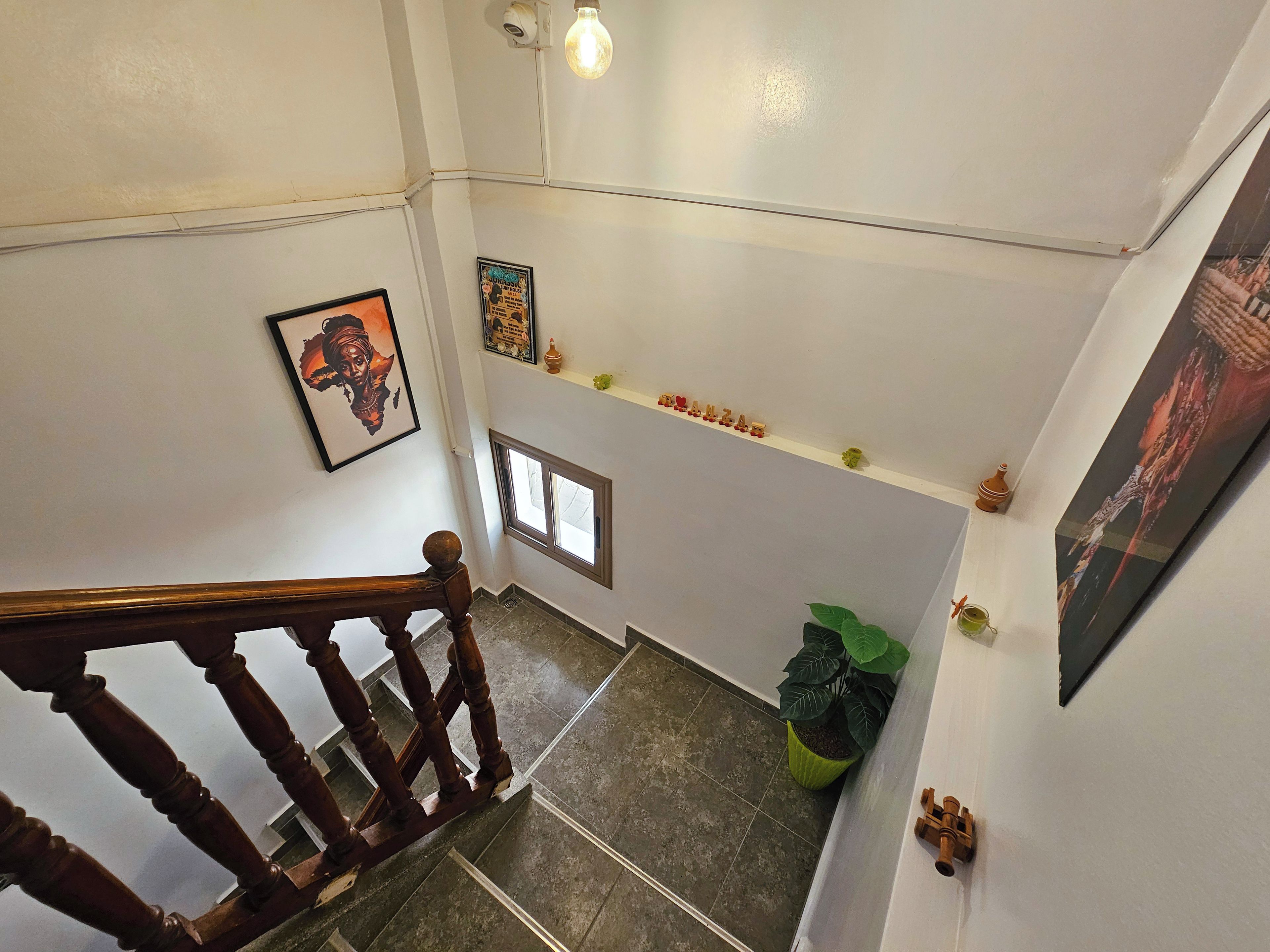 Eine Treppe mit hölzernem Geländer, einem Blumentopf und einem Regal mit Dekoration.