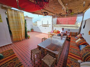 Un área de estar al aire libre acogedora, con una mesa de madera, sillas tejidas y cojines de colores.