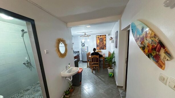 A hallway leading to a dining area with a sink, chairs, and a table. - Jurassic Surf House Anza (Agadir)