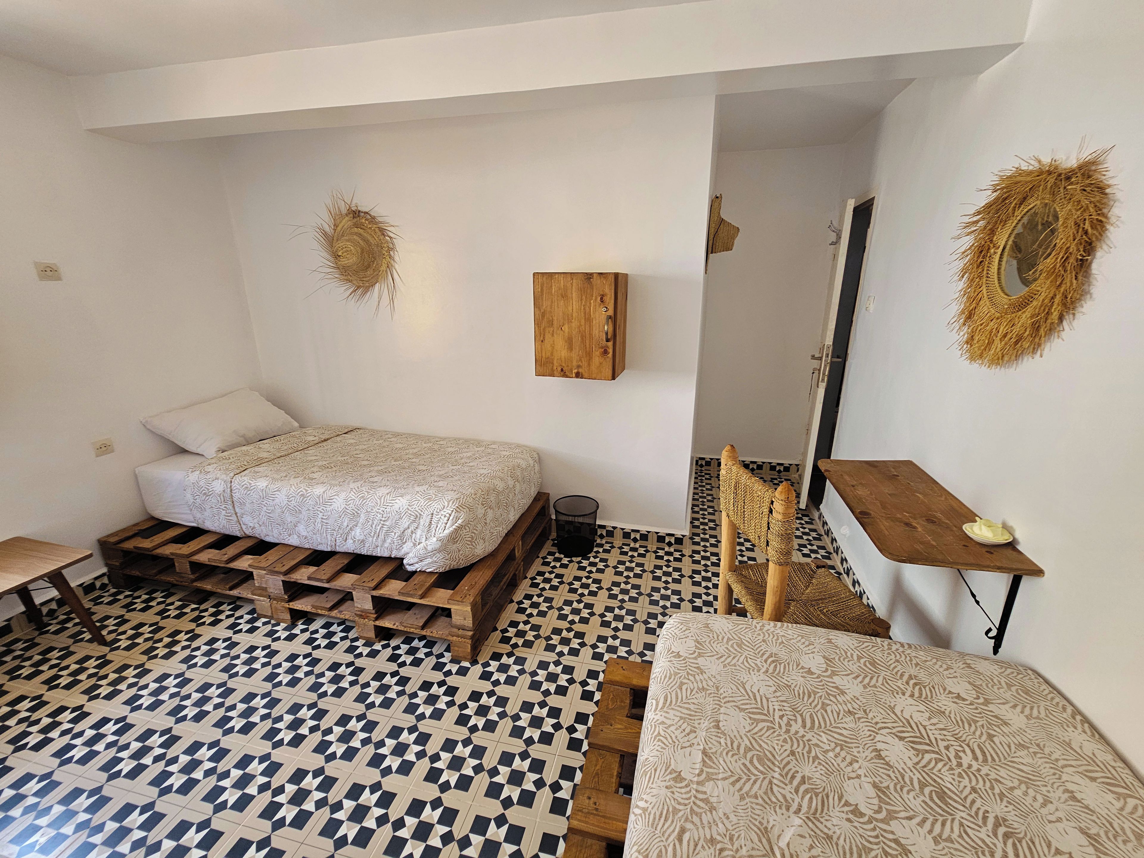 Een slaapkamer met een bed, een houten bankje, een tafeltje en een spiegel.