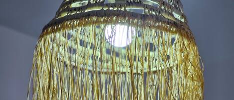 A hanging light fixture with a woven pattern and tassels.