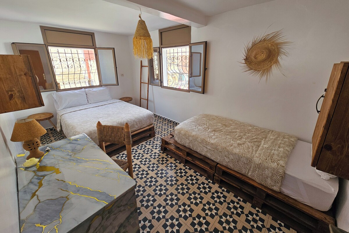 Un dormitorio con cama, una mesita, una silla, un armario de madera y un adorno en la pared.