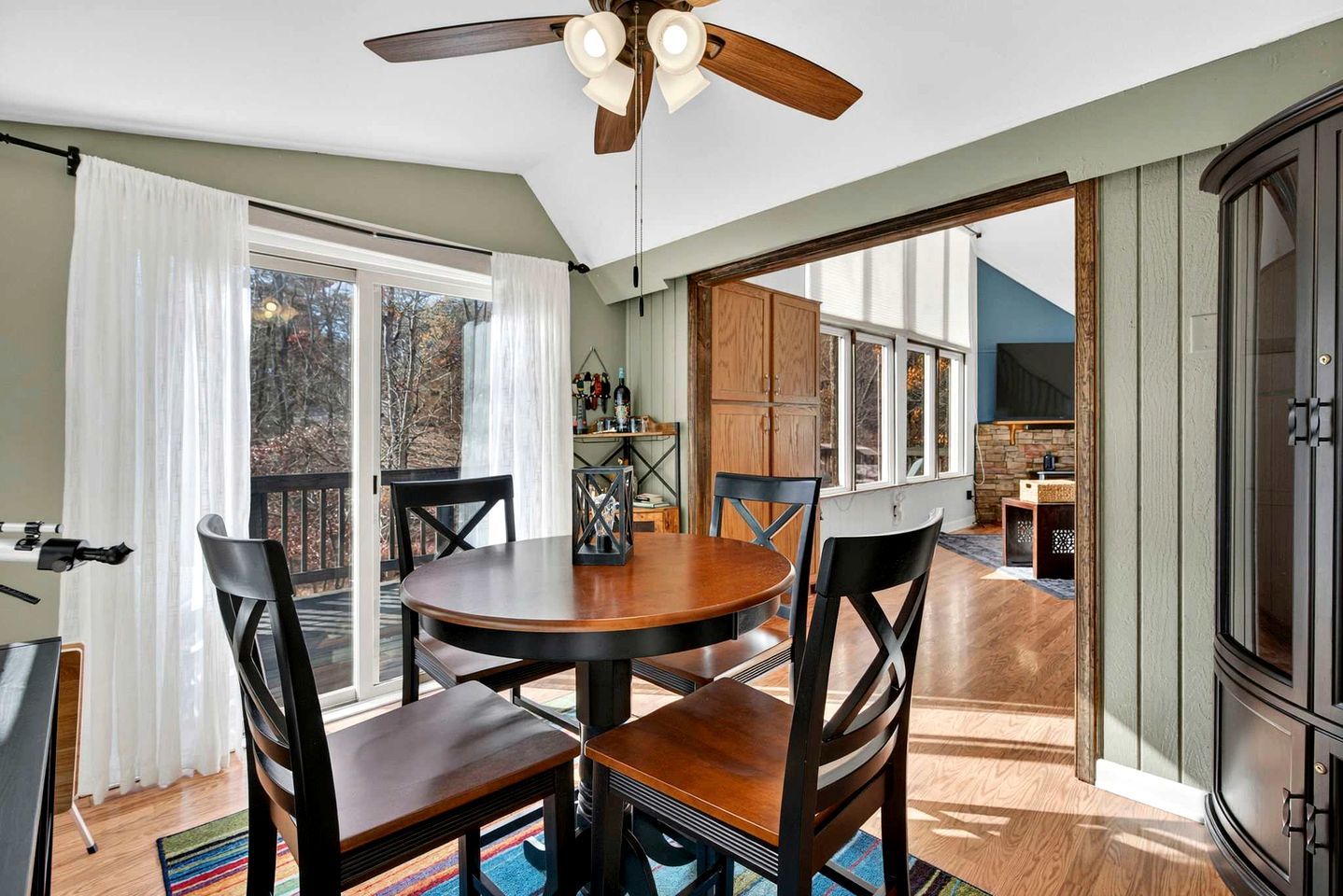A dining area with a round table, four chairs, a ceiling fan, and a view of the outdoors.