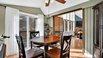 A dining area with a round table, four chairs, a ceiling fan, and a view of the outdoors.