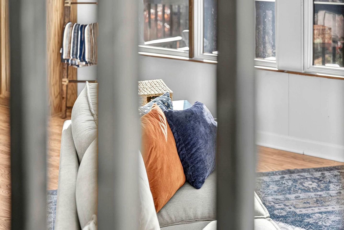 A room with a sofa, pillows, a small table, and a window with a view.