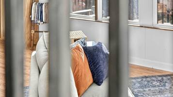 A room with a sofa, pillows, a small table, and a window with a view.