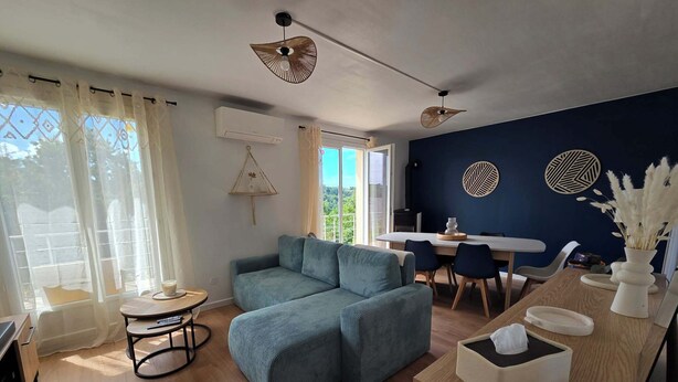 A modern living room with a sofa, a dining table, and a kitchen area.