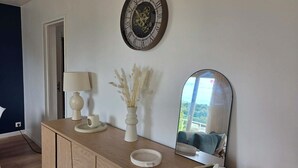A wooden console table with a clock, a vase with dried plants, a mirror, and a tissue box.