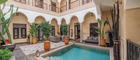 Un cortile con piscina, piante in vaso e zone relax.