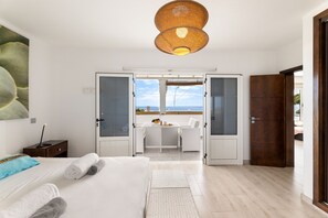 A hotel room with a bed, a desk, and a view of the sea through open doors. - Casa Foti Puerto del Carmen - Media estancia (Puerto del Carmen)