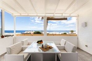 A covered outdoor seating area with a table, chairs, and a view of the sea. - Casa Foti Puerto del Carmen - Media estancia (Puerto del Carmen)