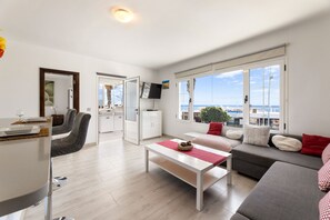 A modern living room with a sofa, a coffee table, and a dining area with chairs and a table. - Casa Foti Puerto del Carmen - Media estancia (Puerto del Carmen)