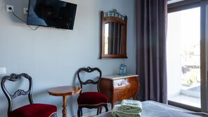 A hotel room with a bed, a television, a dresser, a mirror, a table, two chairs, and a window with curtains.