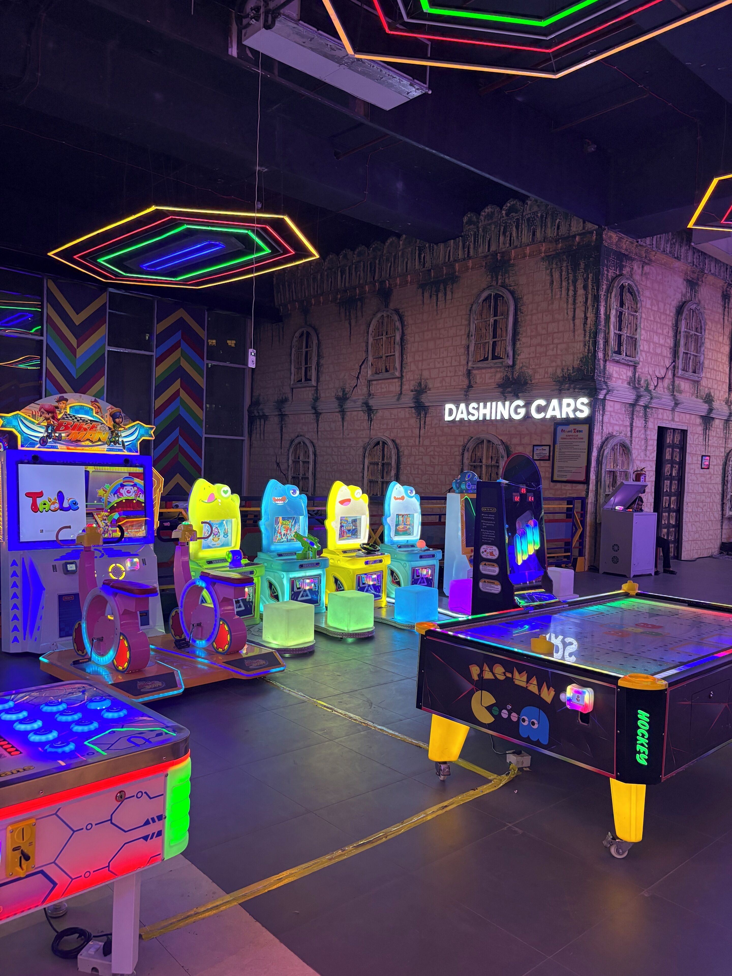 An arcade with various gaming machines, including racing games, and a sign that reads 'DASHING CARS'.