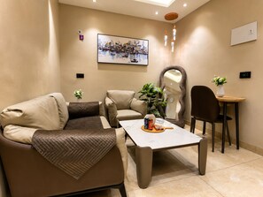 A modern living room with a sofa, coffee table, and a dining area with a chair and table. - Cozy and luxurious studio apartment with balcony in adorable Greater Noida. (Greater Noida)