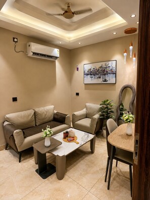 A modern living room with a sofa, armchair, coffee table, and a dining table with chairs.