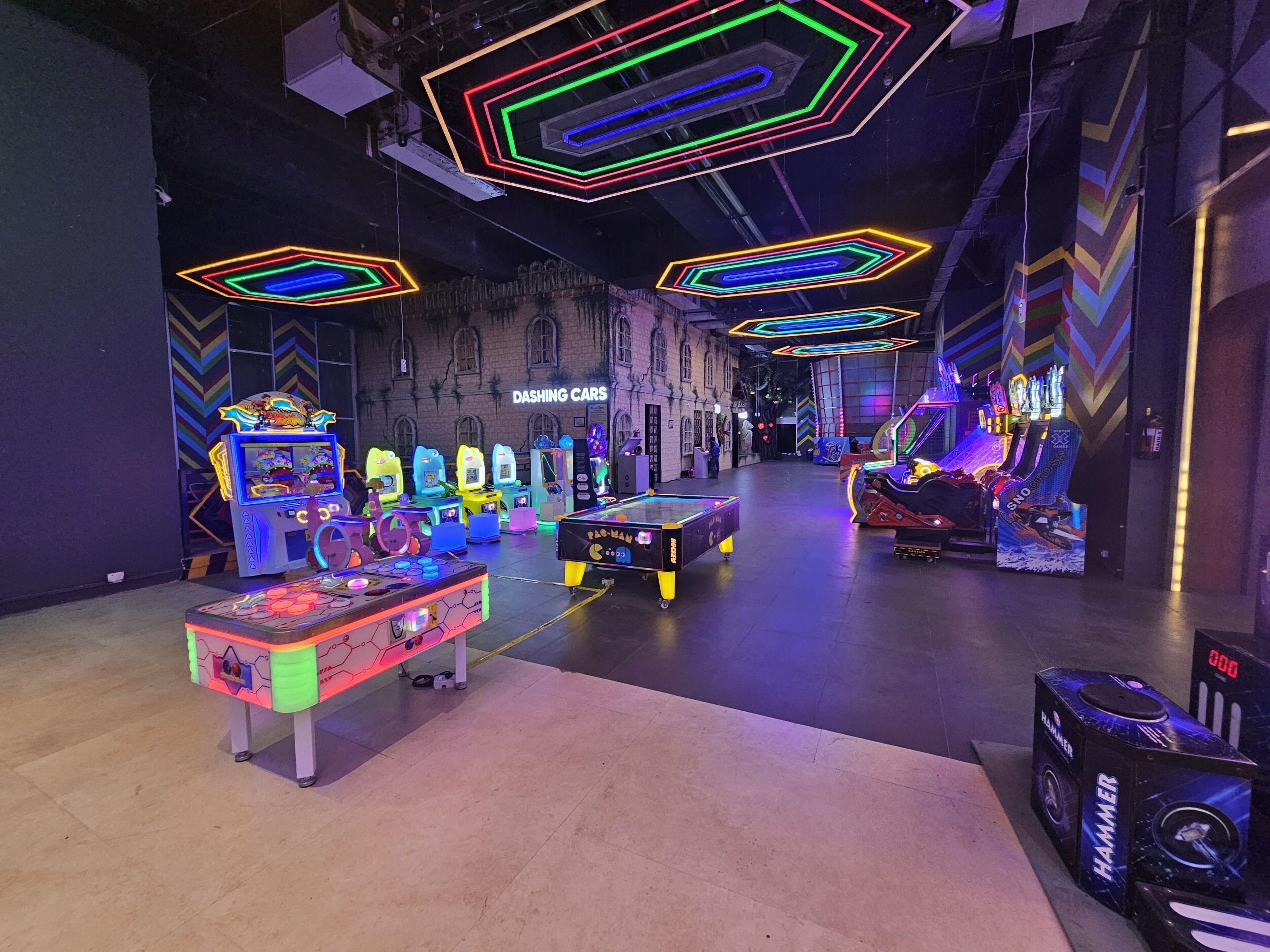 An indoor arcade with neon lights and various gaming machines.