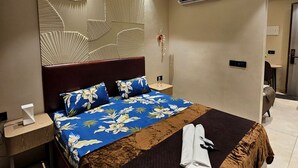 Una camera d'albergo moderna con un letto grande, un comodino, un condizionatore d'aria e una ventola a soffitto.