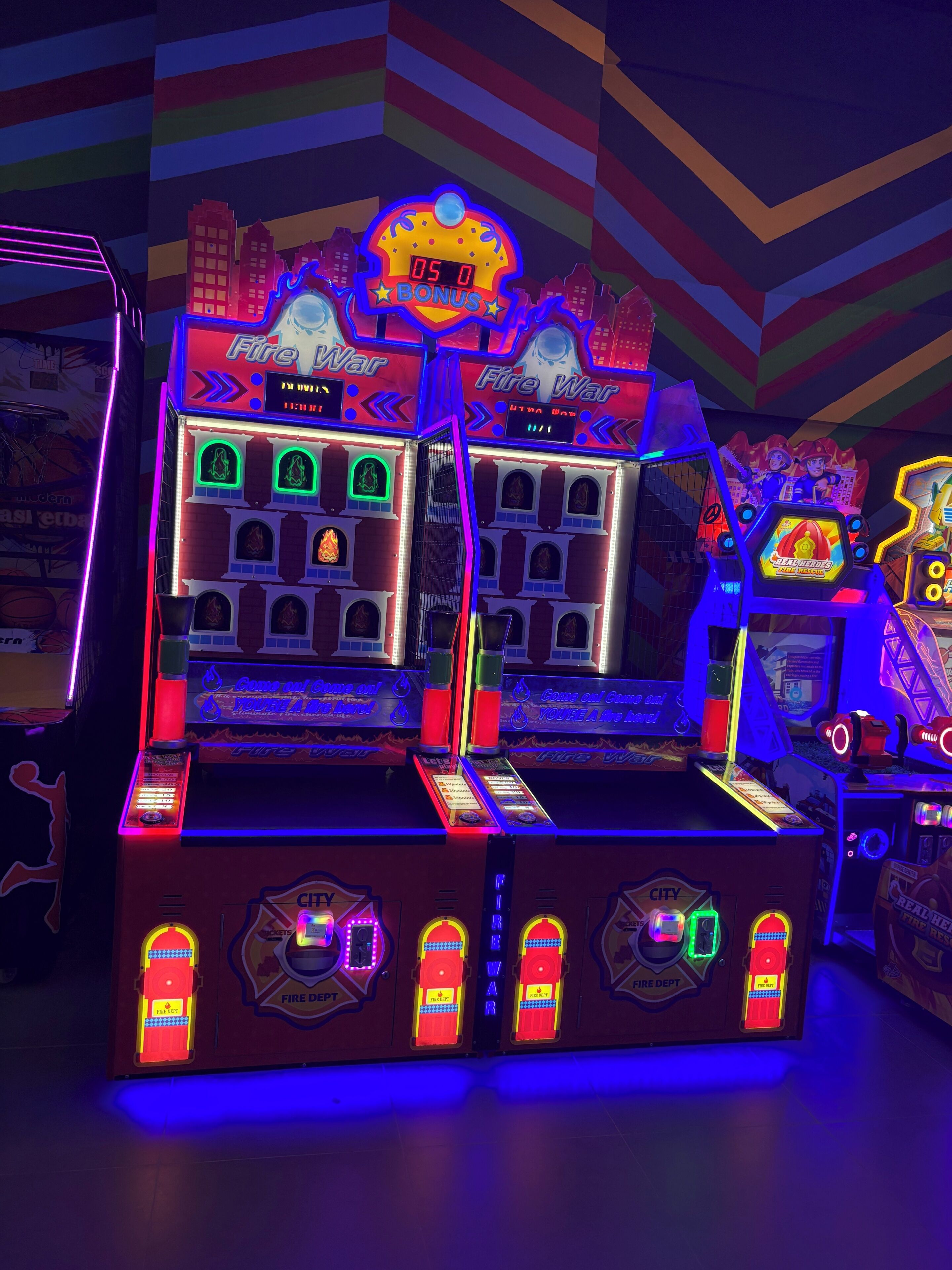 Een felverlichte speelautomaat met een brandweerthema, inclusief neonverlichting en een scorebord.