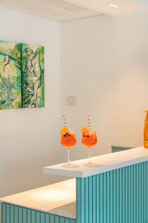 Un espace d’accueil avec un comptoir, deux boissons servies avec des pailles et un tableau accroché au mur.
