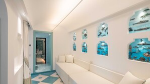 Ein Flur mit einem weißen Sofa, einem gemusterten Boden und Wandbildern, die Unterwasserwelten zeigen.