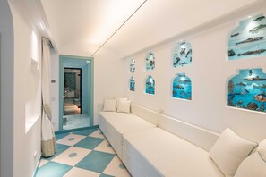Ein Flur mit einem weißen Sofa, einem gemusterten Boden und Wandbildern, die Unterwasserwelten zeigen.