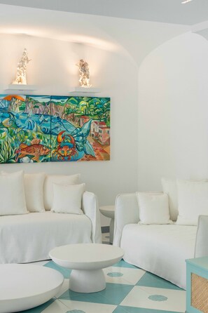 A modern living room with white sofas, a round coffee table, and a colorful mural on the wall. - Estate4home - Villa Nerea (Massa Lubrense)