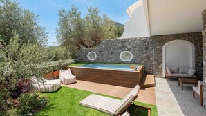 Ein Pool mit Steinmauer, Sitzgelegenheiten im Freien und Blick auf Bäume und Berge.