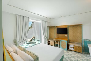 Ein Hotelzimmer mit Bett, Schreibtisch, Fernseher und Blick ins Freie.