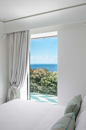 Une chambre avec un grand lit, une fenêtre avec des rideaux et une vue sur la mer.