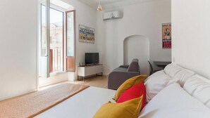 Ett modernt hotellrum med en säng, ett skrivbord med en dator, en stol och en tv.