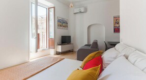 Quarto de hotel moderno com uma cama, uma escrivaninha com computador, uma cadeira e uma televisão.