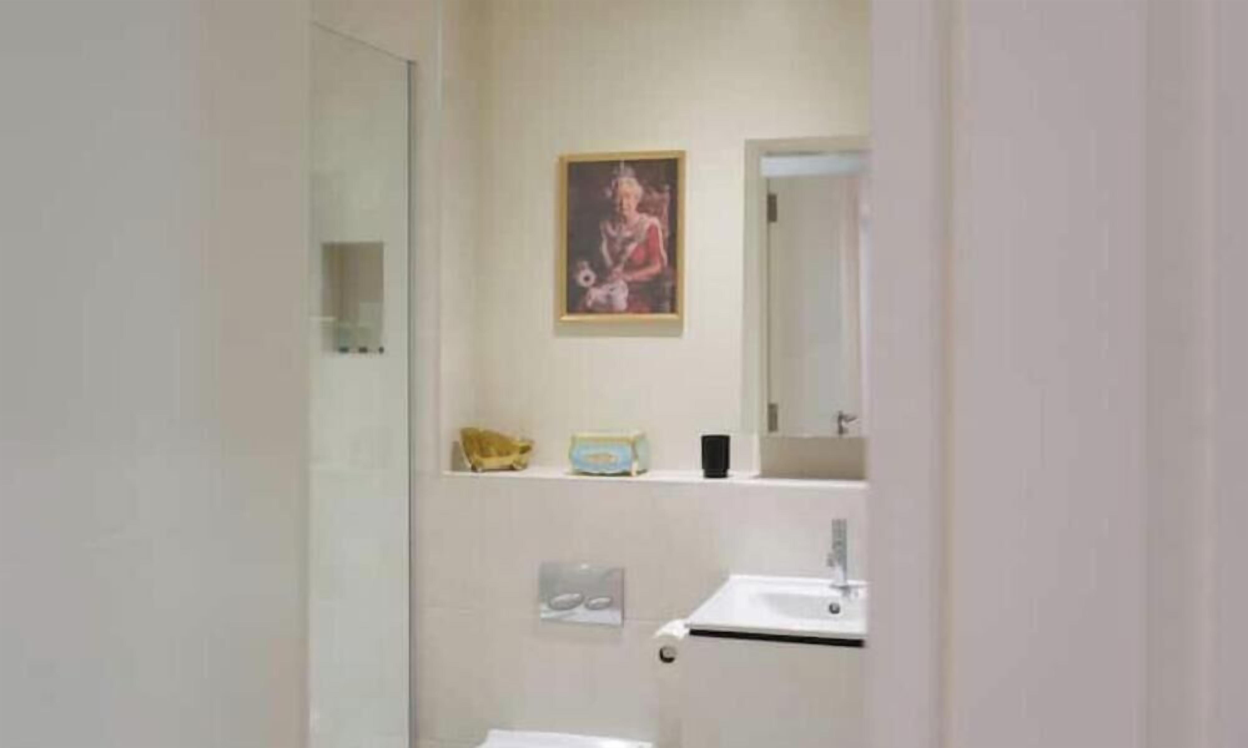 A bathroom with a sink, mirror, and a framed picture on the wall.