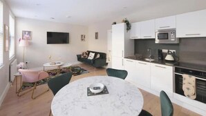 Una cucina moderna con mobili bianchi, un forno a microonde integrato e un piano cottura. C'è un'area pranzo con un tavolo rotondo e sedie.