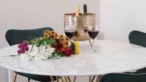 Un tavolo rotondo con piano in marmo, due sedie, un bouquet di fiori, una bottiglia di champagne e due bicchieri da vino.