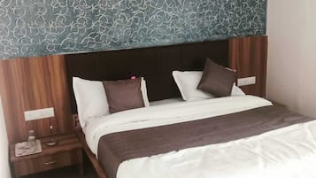 A hotel room with a large bed, wooden headboard, and a patterned wall above the bed.