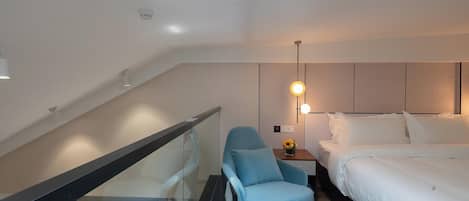 A hotel room with a bed, a chair, a nightstand, and a small table.