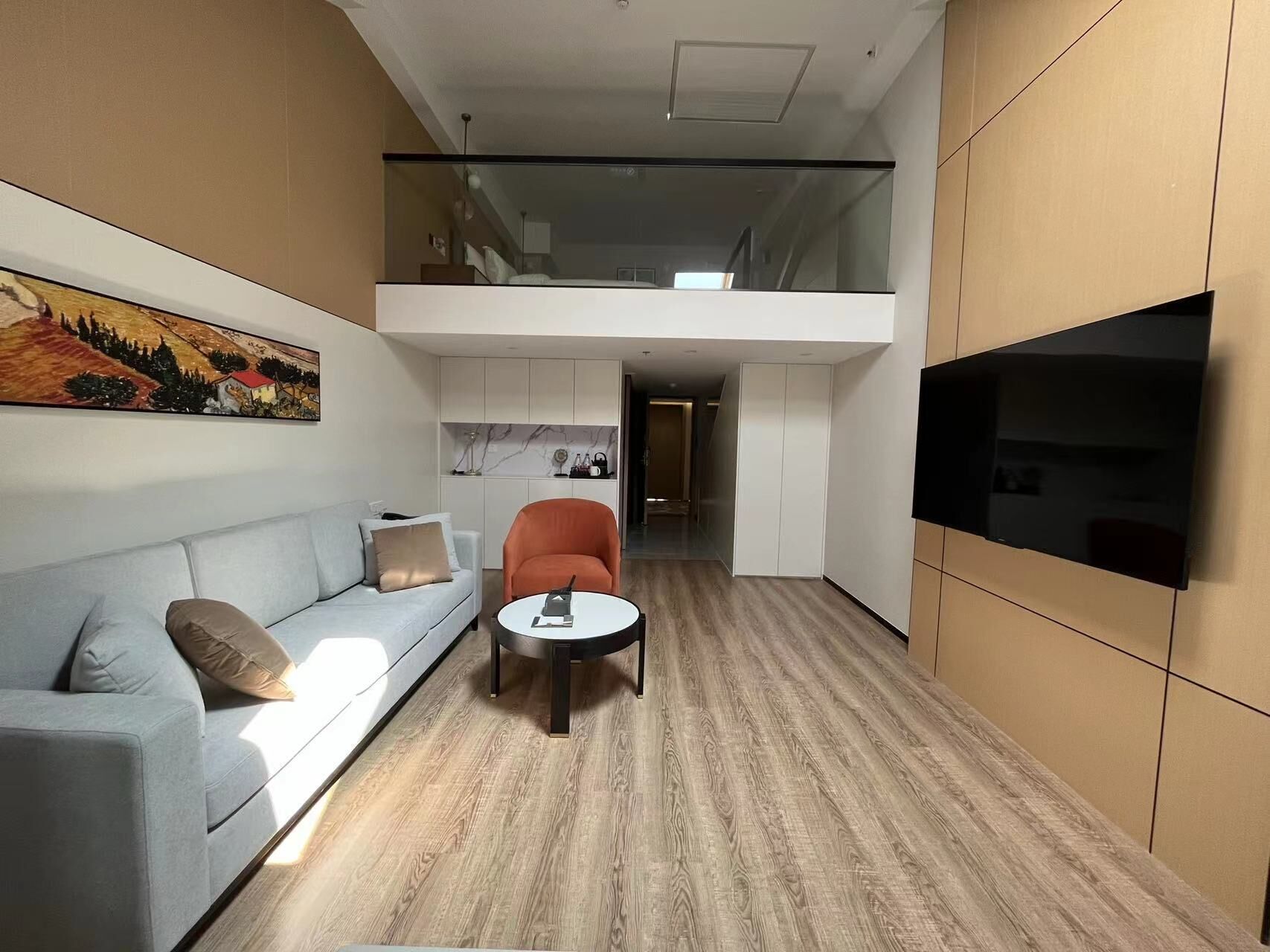 A modern interior with a sofa, a chair, a small table, and a TV mounted on the wall.