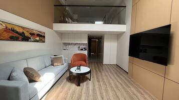 A modern interior with a sofa, a chair, a small table, and a TV mounted on the wall.