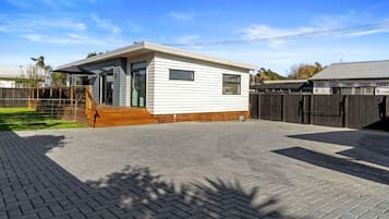 Une maison mobile de plain-pied, dotée d’un porche à l’avant et d’une allée pavée.