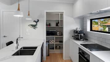 A modern kitchen with white cabinetry, a built-in oven, a coffee machine, and a window with a view.
