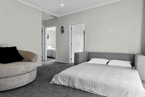 A bedroom with a bed, a chair, and a door leading to another room.