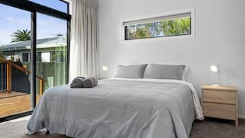 Une chambre à coucher avec un lit, deux tables de chevet, une fenêtre et une vue sur une terrasse.