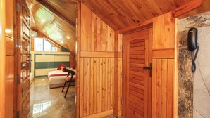 A wooden interior with a bed, a chair, and a telephone. - BR Resort (Dharamshala)