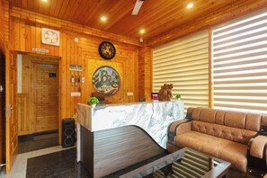 A reception area with a wooden interior, a reception desk, a couch, and a clock on the wall.
