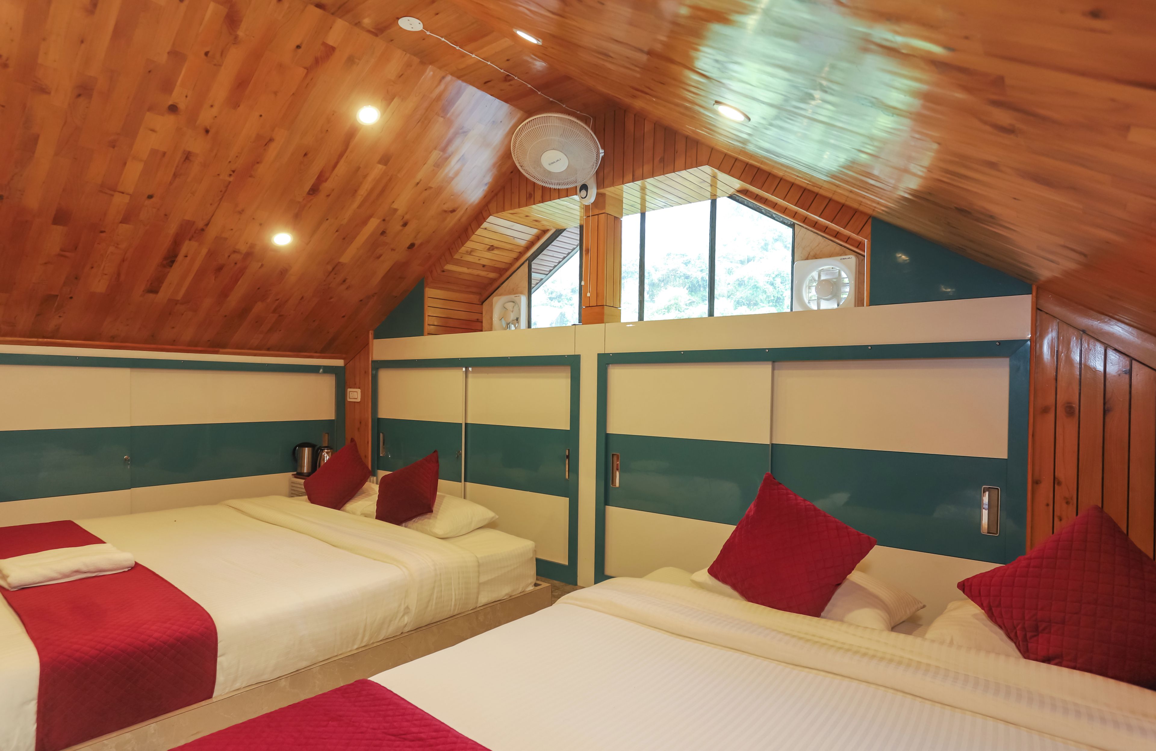 Une chambre avec deux lits, un ventilateur de plafond et une fenêtre.